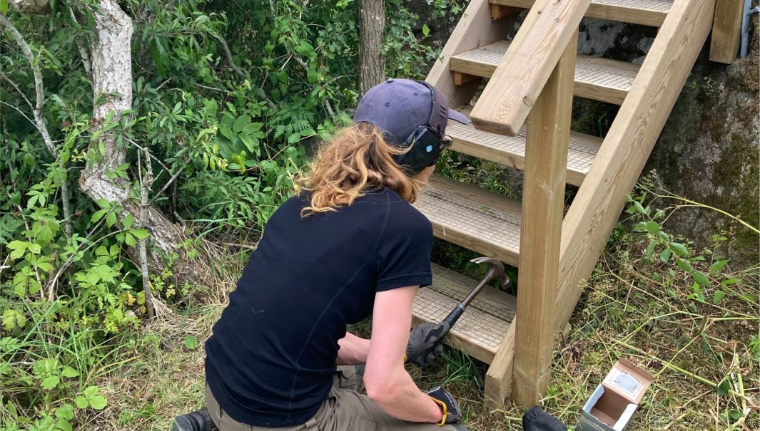 Perso spikar ett nät på ett trappsteg. Foto.