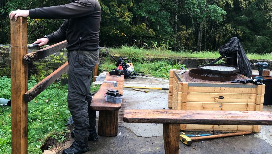 Person bygger ett räcke intill ny eldplats. Foto.