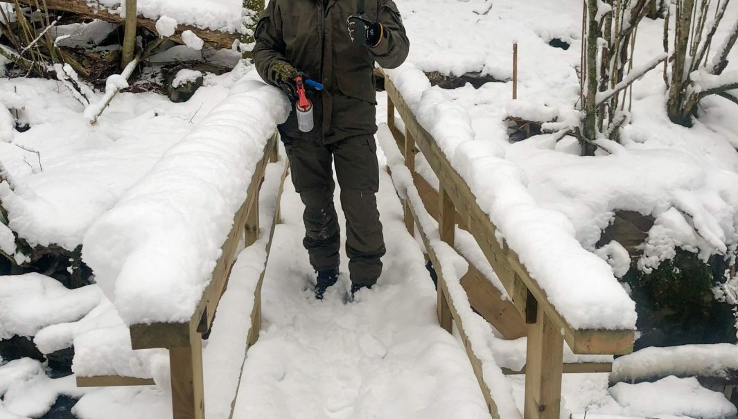 Person står på bro och visar tummen upp. Foto.