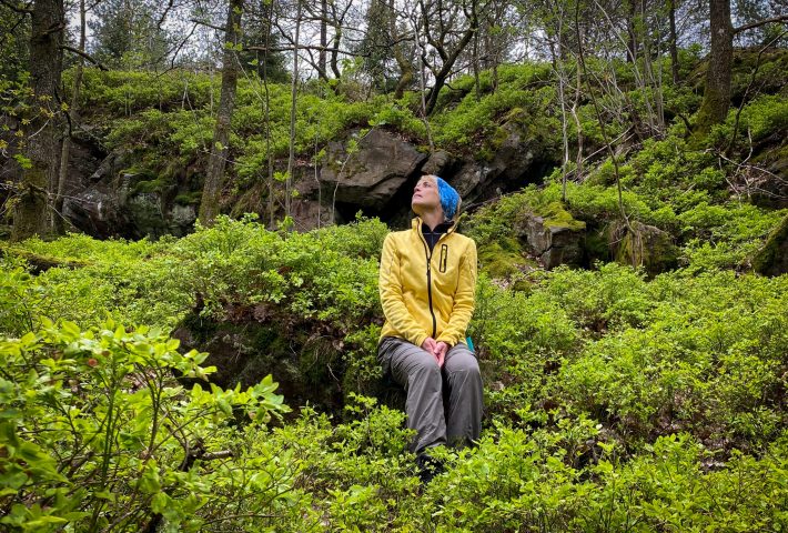 Person sitter i skogen och super in atmosfären. Foto.