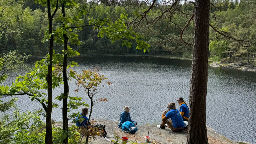 En grupp personer som fikar vid en sjö. Foto.