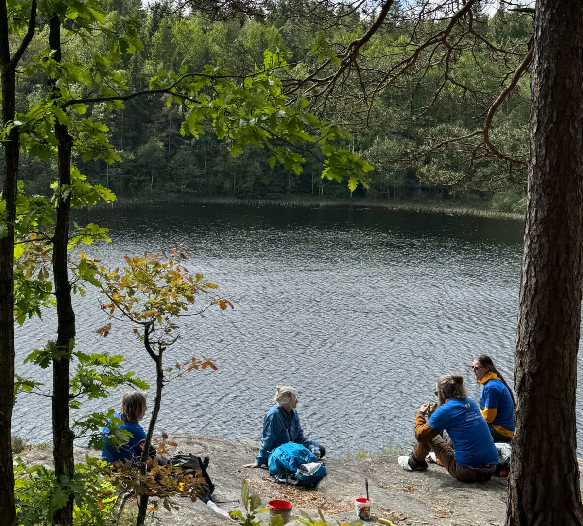 En grupp personer som fikar vid en sjö. Foto.