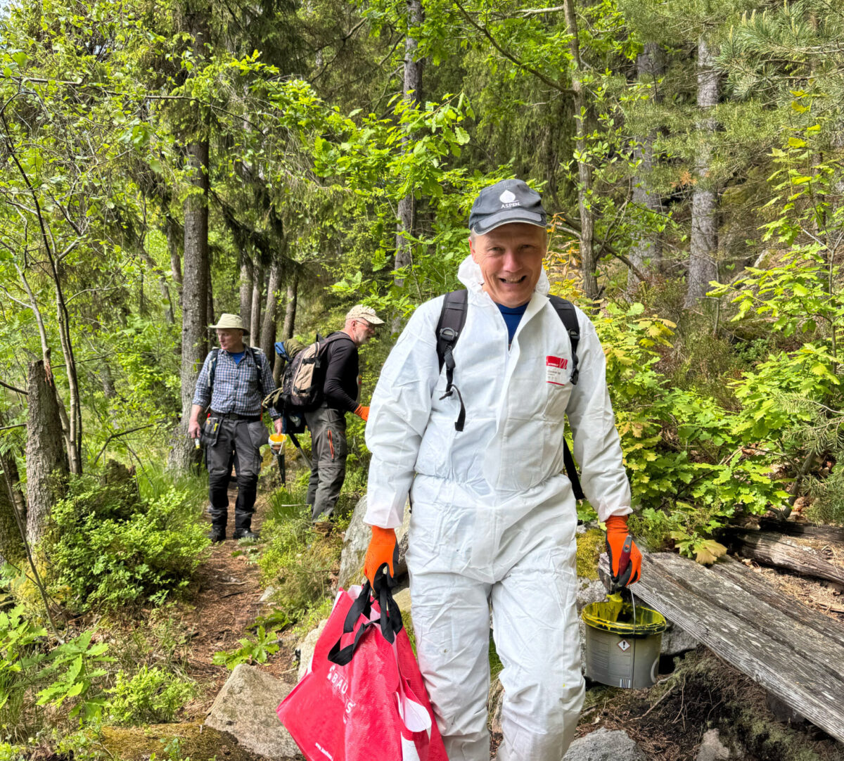 Personer går längs med en stig med penslar och målafärg. Foto.
