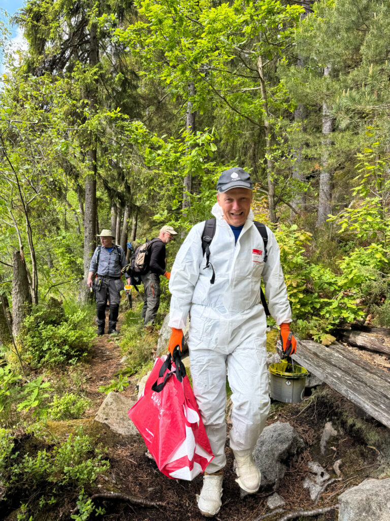 Personer går längs med en stig med penslar och målafärg. Foto.