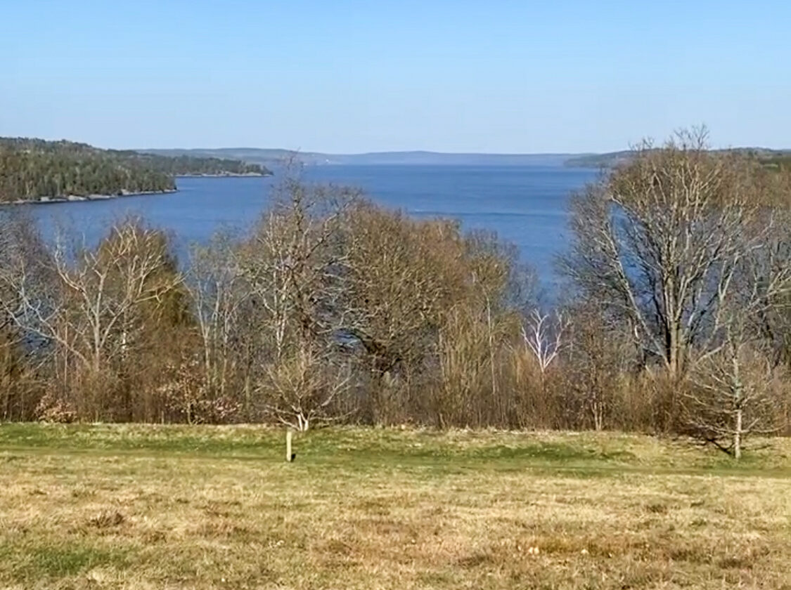 Utsikt från en höjd ner mot en sjö. Foto.